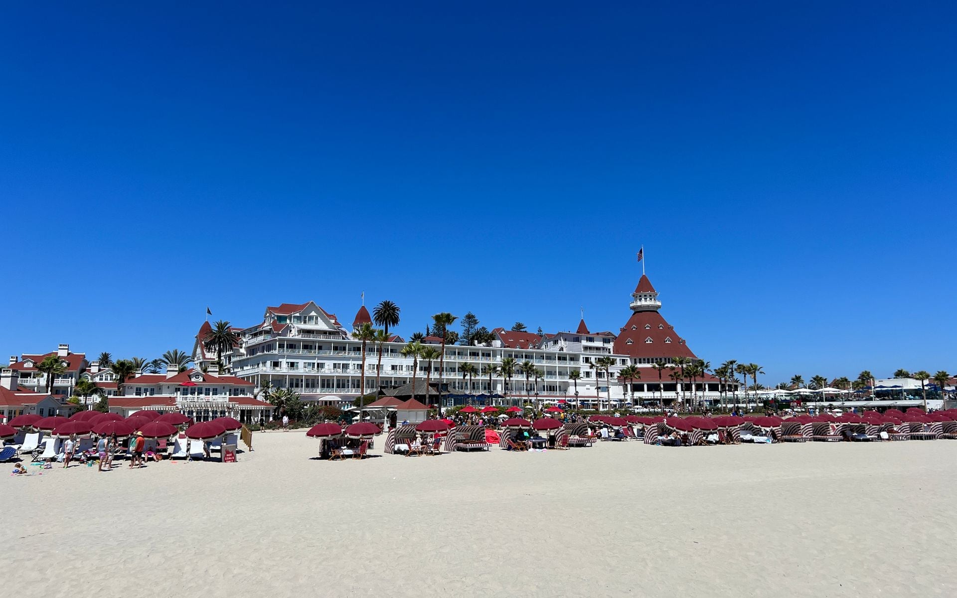 Wide golden sand at Coronado Beach in San Diego with the Hotel del Coronado's red turrets behind it