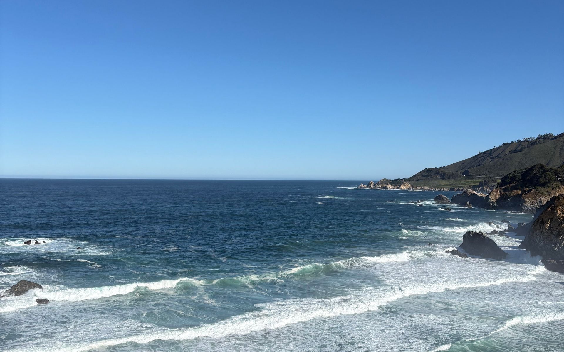 Clear autumn afternoon on Highway 1 above the Big Sur coast with the ocean visible to the horizon