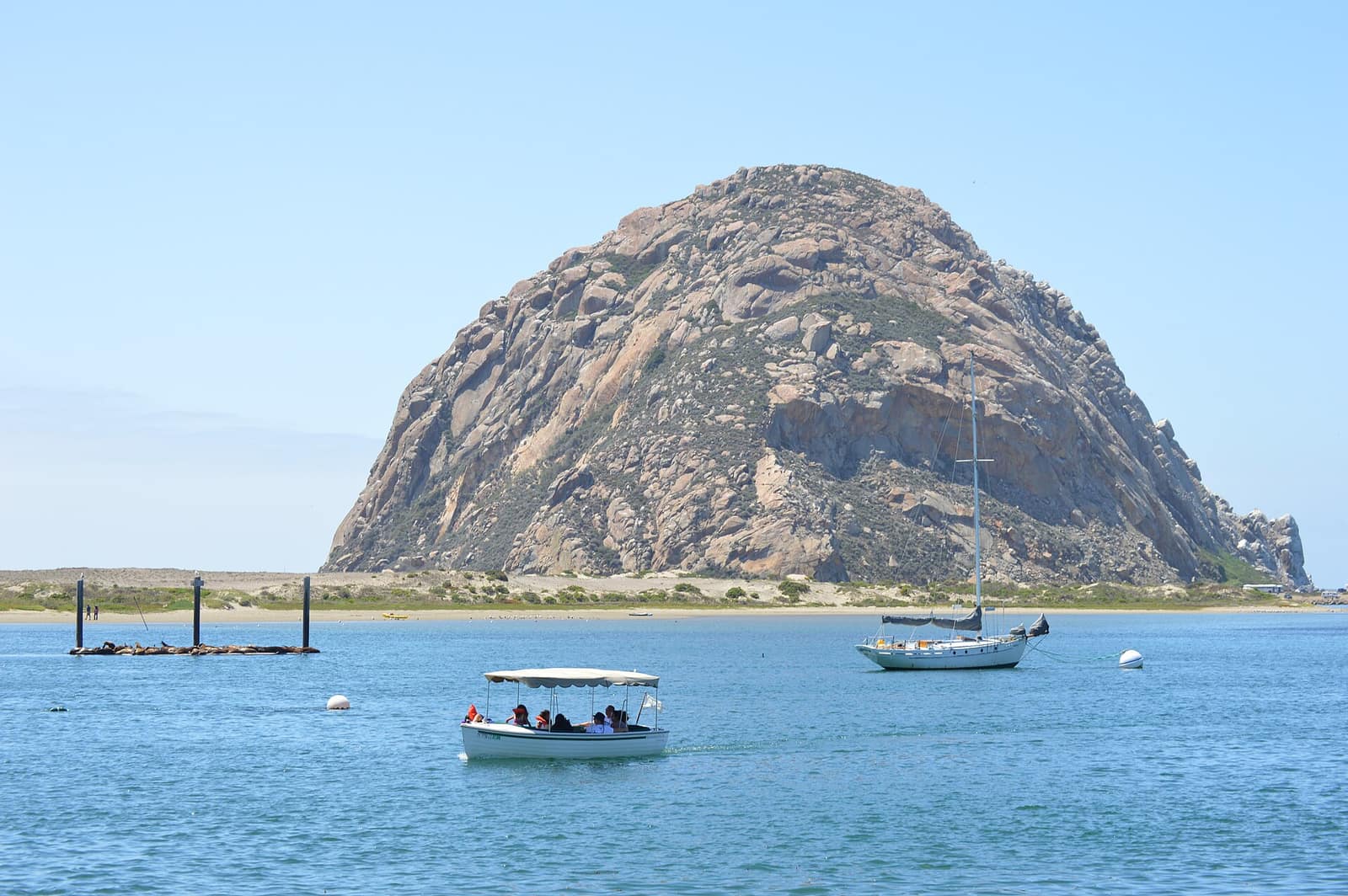 Morro Rock rising above the calm waters of Morro Bay with a small tour boat and sailboat in the foreground, San Luis Obispo County, California